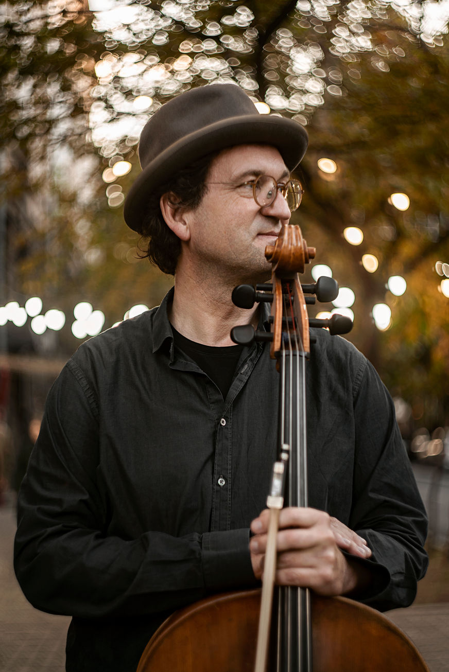 Cellist mit Hut schaut nach rechts aus dem Bild