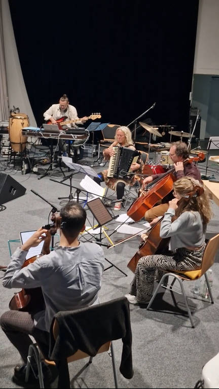 Musiker auf Theaterbühne Celli, Akkordeon vorn. Bass und schlagzeug hinten