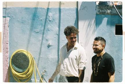 zwei Musiker und ein gelder Wasserschlauch vor blauer Wand. Die Sonne scheint in Lissabon. ein Foto als Gemäldestimmung